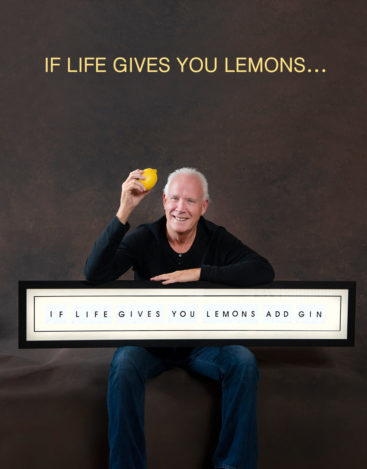 Man holding a lemon with text 'If life gives you lemons add gin' on a dark brown fabric background