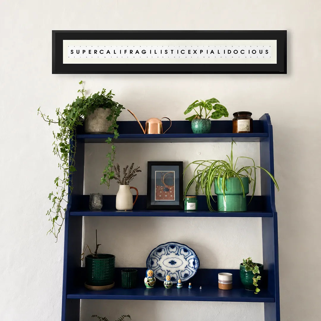 SUPERCALIFRAGILISTICEXPIALIDOCOUS playing card frame quote hanging above a blue shelving unit with plants and decorative items
