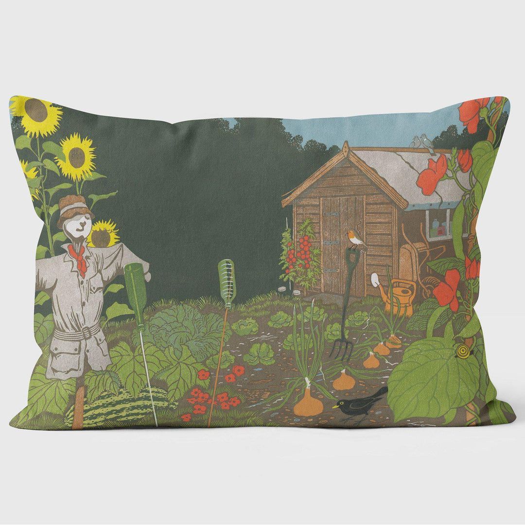 Cushion with a scarecrow, shed and rows of vegetables growing in the ground.