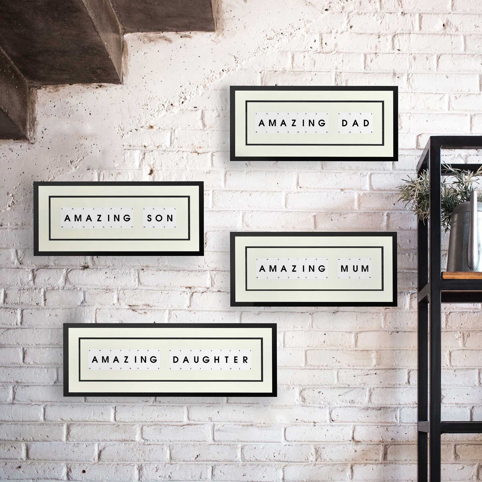 Amazing Mum, Amazing Dad, Amazing Son and Amazing Daughter playing card picture frames displayed on a white brick wall under some stairs.