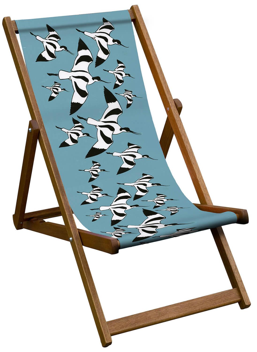 A deckchair with a flock of black and white avocets on a blue sling.