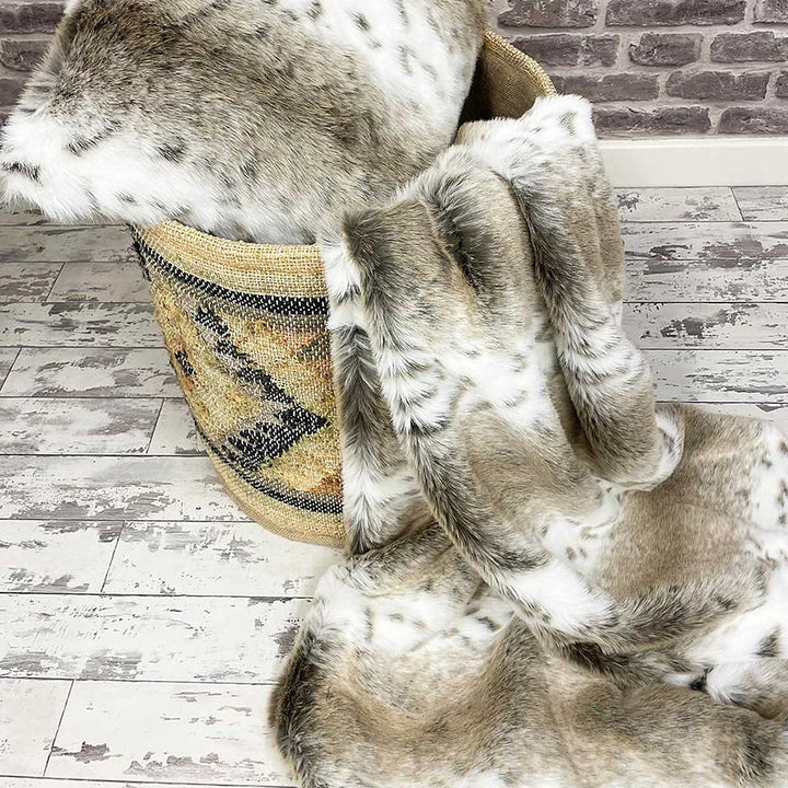 Soft beige and white faux fur throw lynx pattern draped over large basket