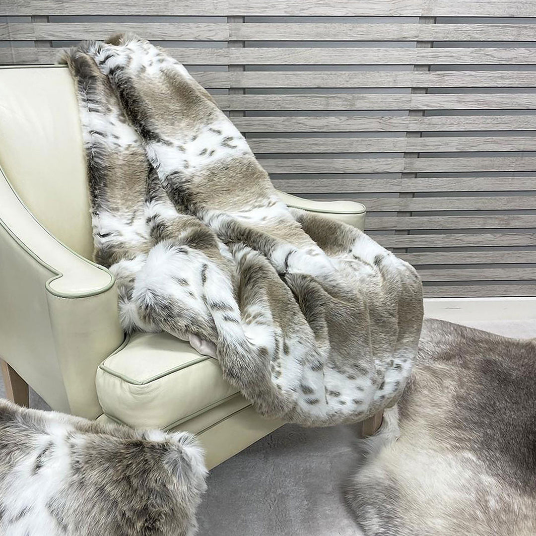 Beige lynx faux fur throw folded on a chair