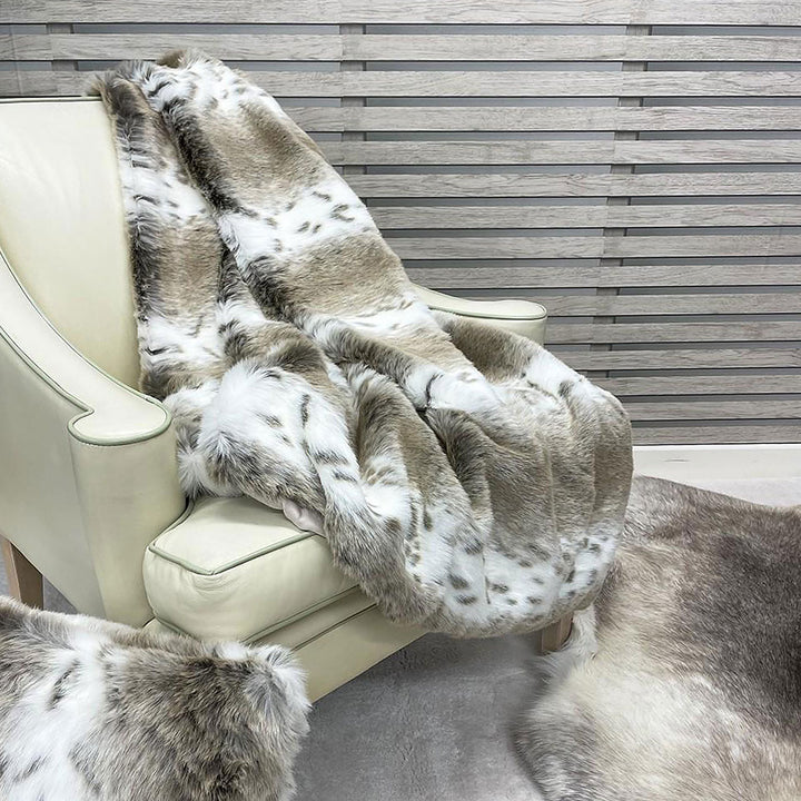 Beige lynx faux fur throw folded on a chair