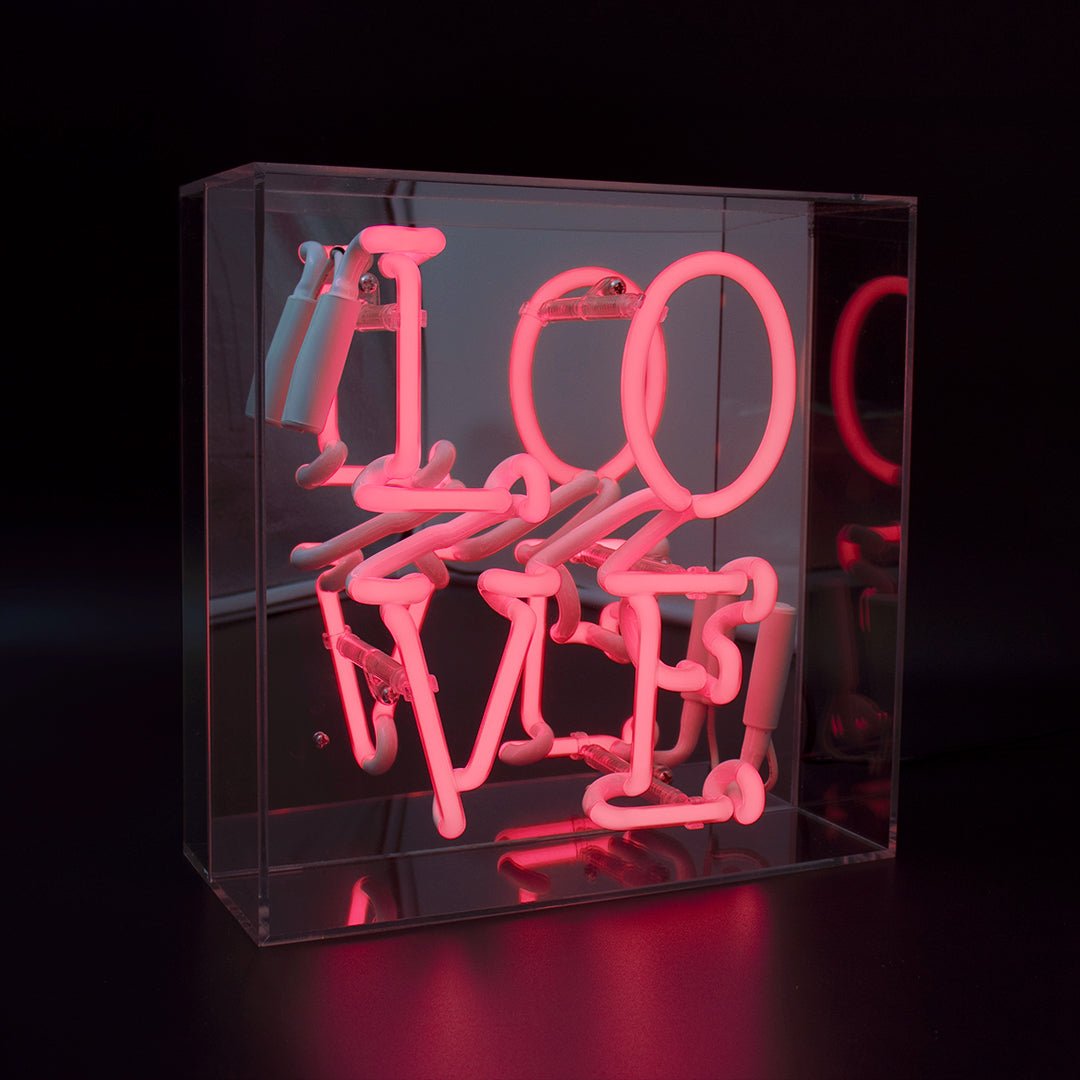 Angled view of Love Mini Neon Sign in pink, mounted on tabletop