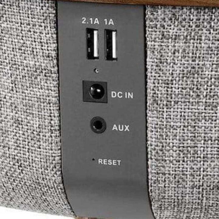 Tabblue Bluetooth Table Speaker wood finish showing ports labeled DC IN, AUX, and RESET on a textured gray fabric surface.